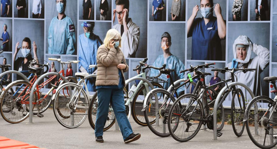 A woman walks past a display of photos outside the Royal Melbourne Hospital on October 20, 2020, to thank healthcare workers as the state of Victoria records one new case of the COVID-19 coronavirus.