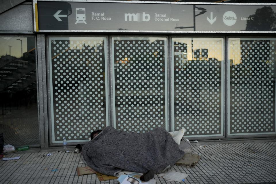 A man sleeps at a subway station entrance that is closed due to a general strike against the reforms of President Javier Milei in Buenos Aires, Argentina, Thursday, May 9, 2024. (AP Photo/Natacha Pisarenko)