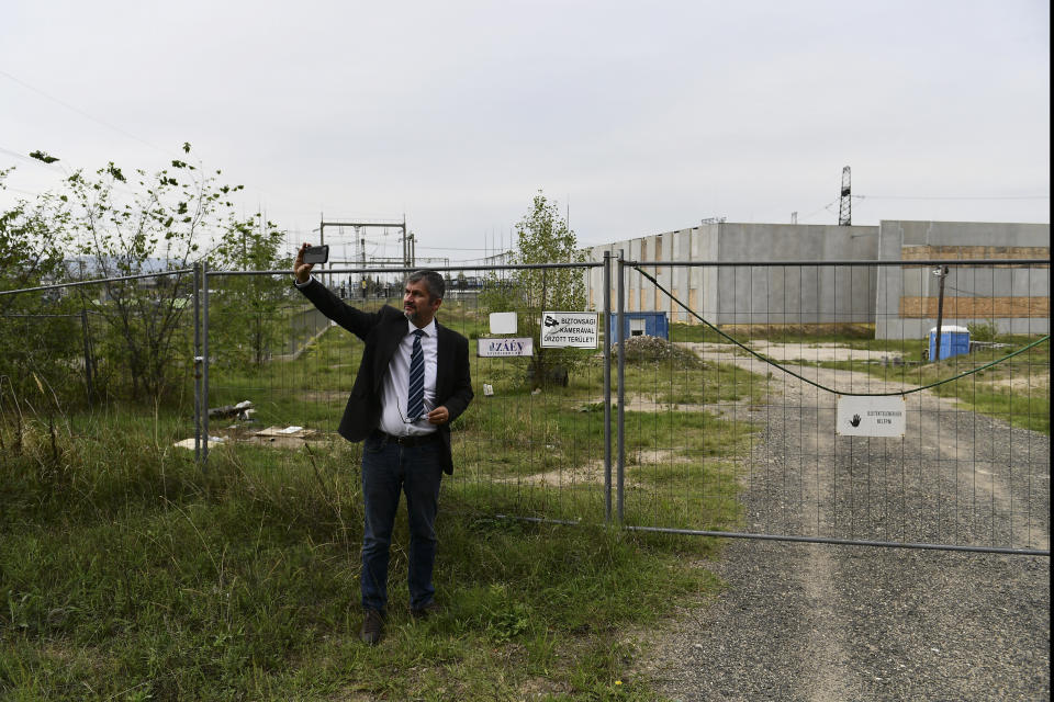 Independent lawmaker Akos Hadhazy, who has made a name for himself in Hungary as an anti-corruption crusader, snaps pictures at the site of a planned, but never finished government server farm to store the state's important data in God, Hungary, Wednesday, Sept. 14, 2022. The construction received nearly $40 million in EU funding in 2016, but was never finished, which Hadhazy says a clear sign of the missuse of EU funds. Hungarian prime minister Viktor Orban is facing a reckoning with the EU, which appears set to impose financial penalties on Hungary over corruption concerns and alleged rule-of-law violations that could cost Budapest billions and cripple its already ailing economy. (AP Photo/Anna Szilagyi)