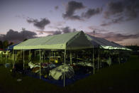 Tents and cots are set up for people whose homes are either destroyed or unsafe to enter after an 6.4 magnitude earthquake, at a baseball stadium amid aftershocks and no electricity in Guayanilla, Puerto Rico, at sunrise Friday, Jan. 10, 2020. Hundreds of thousands of Puerto Ricans are still without power and water, and thousands are staying in shelters and sleeping on sidewalks since Tuesday’s earthquake. (AP Photo/Carlos Giusti)