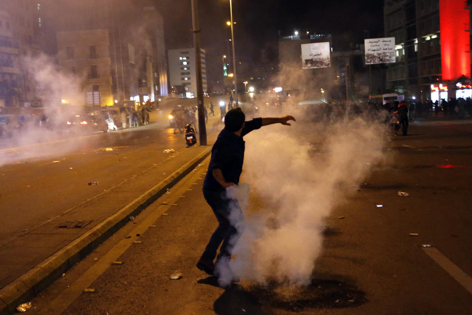 A protester throws back tear gas canister that was fired towards them by Lebanese riot police during an anti-government protest in Beirut, Lebanon, Wednesday, Dec. 4, 2019. Protesters have been holding demonstrations since Oct. 17 demanding an end to corruption and mismanagement by the political elite that has ruled the country for three decades. (AP Photo/Bilal Hussein)