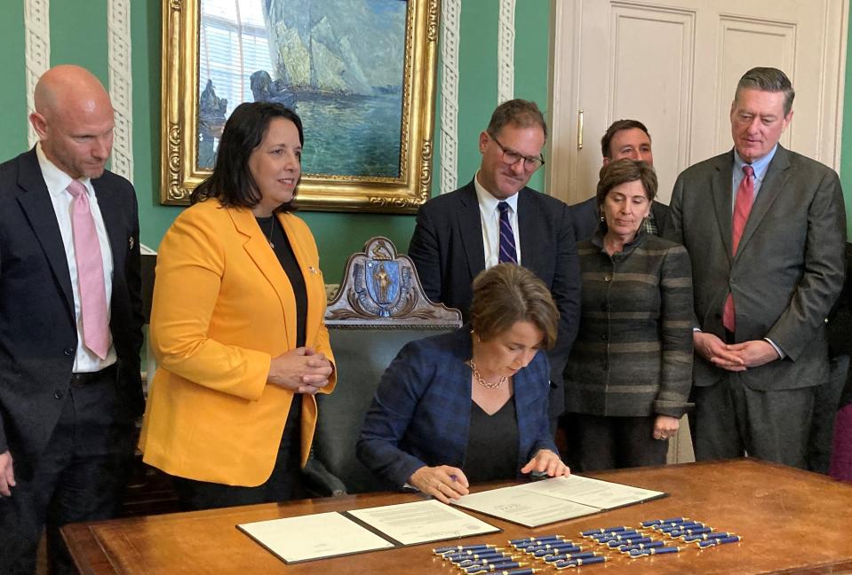 Flanked by members of her administration, Gov. Maura Healey signs the paperwork that memorializes the Office of Federal Funds & Infrastructure and its director, Quentin Palfrey.