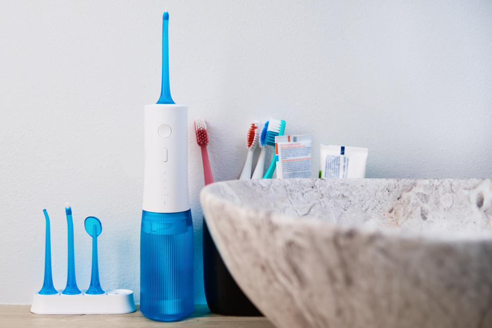 An electric toothbrush, a manual one, and dental care items are on a bathroom counter