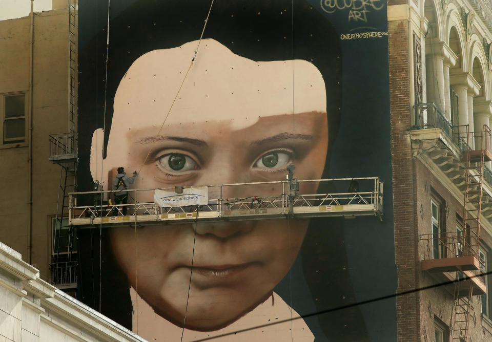 Andres Petreselli paints a mural on the side of a building depicting Swedish teen climate activist Greta Thunberg, Friday, Nov. 8, 2019, in San Francisco. (AP Photo/Ben Margot)