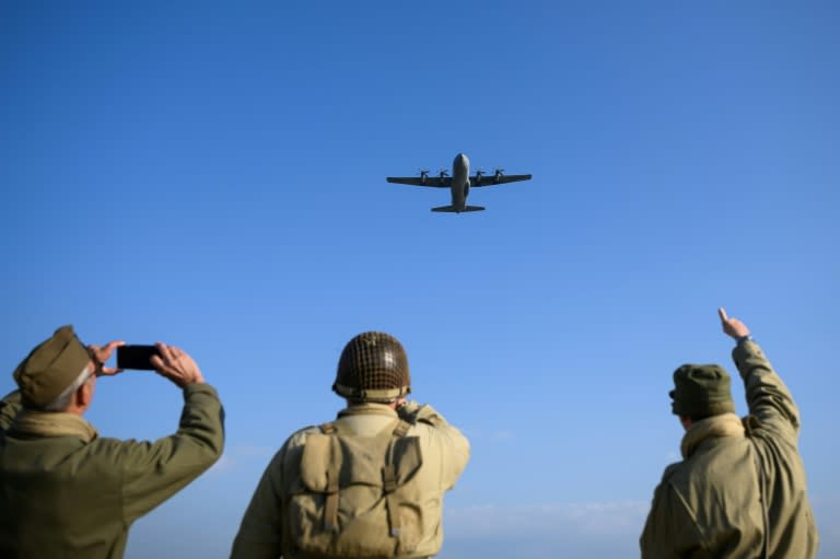 Tres personas con uniformes militares estadounidenses de la Segunda Guerra Mundial observan un avión Lockheed C-130 Hércules en la playa de Utah, en Francia, el 6 de junio de 2024, durante la conmemoración de los 80 años del Desembarco de Normandía (Loic Venance)