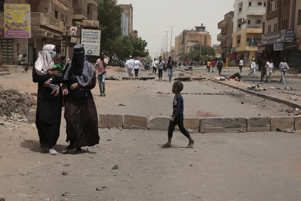 People cross barriers blocking streets during a protest demanding a return to civilian rule and to protest the nine people who were killed in anti-military demonstrations last month, in Khartoum, Sudan, Monday, July 4, 2022. (AP Photo/Marwan Ali)