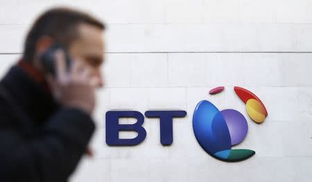 A man talks on his mobile phone as he walks past a BT logo in London, February 5, 2015. REUTERS/Suzanne Plunkett