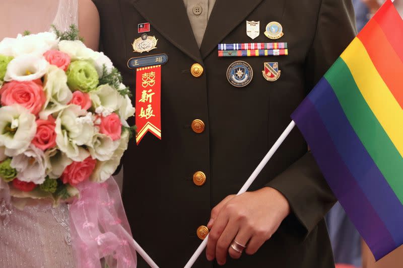 A same-sex couple holds a rainbow flag during a military mass wedding in Taoyuan