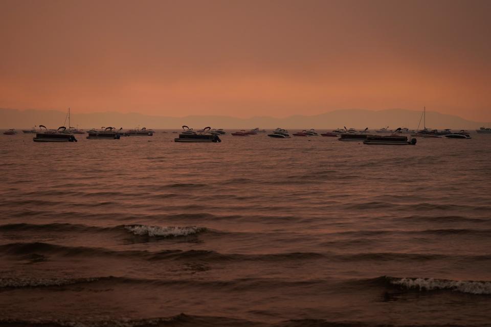 Boats float in the water away from a dock in South Lake Tahoe, Calif., as the Caldor Fire approaches Lake Tahoe.