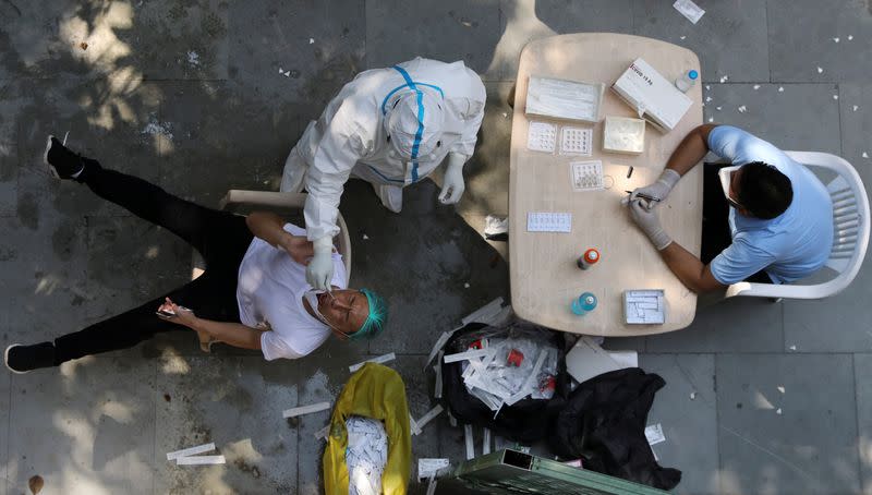 A health worker wearing personal protective equipment (PPE) collects a swab sample from a man in New Delhi