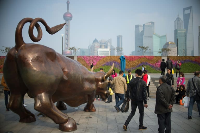 People have photos taken with a replica of the famous Wall Street bronze bull on the Bund in Shanghai on November 17, 2014