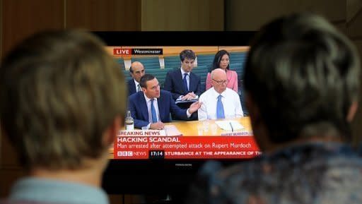 A family in Stockport watch Rupert Murdoch and his son James giving evidence to Britain's Parliamentary Select Committee in July 2011. A British parliamentary report says Rupert Murdoch showed "willful blindness" over phone hacking at his News of the World tabloid and was not fit to run a major company