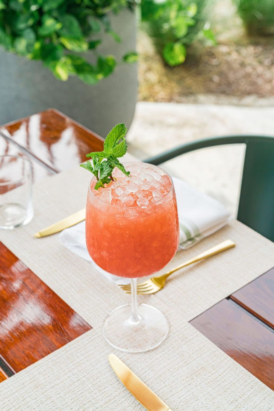 a wine glass with a colorful drink in it sitting on table