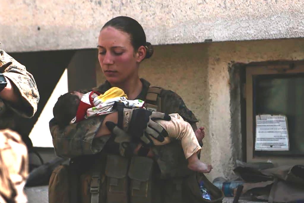 Sgt. Nicole Gee holding a baby at Hamid Karzai International Airport in Kabul, Afghanistan. She was killed Thursday’s blast  (AP)