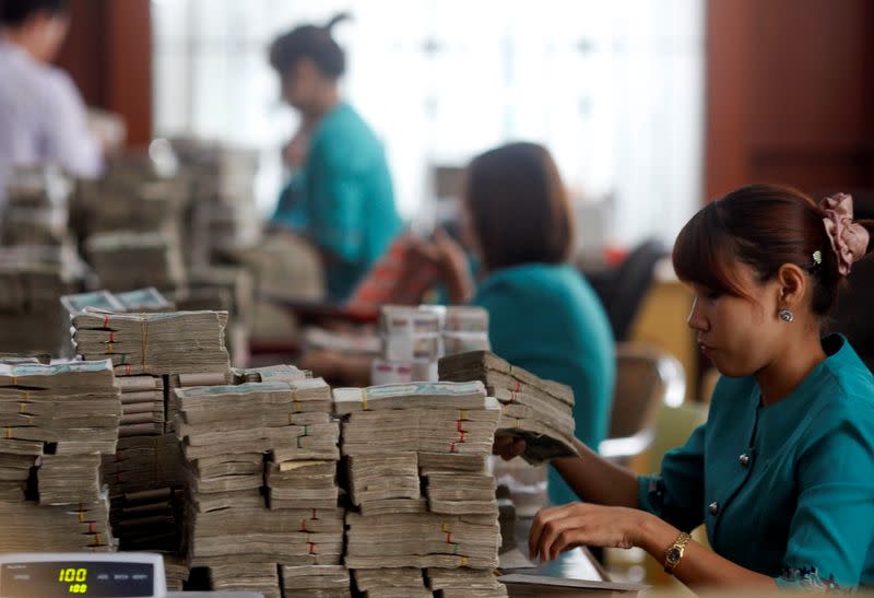 FILE PHOTO: FILE PHOTO: Workers count Myanmar's kyat banknotes at the office of a local bank in Yangon