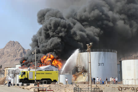 Firefighters try to cool down oil storage tanks adjacent to a tank engulfed by fire at the Aden oil refinery in Aden, Yemen January 12, 2019. REUTERS/Fawaz Salman