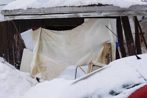 A tarp was thrown over a window smashed by a backhoe at this home on Allandale Road. The tenants say their landlord smashed it out after pushing their car aside with the plow.