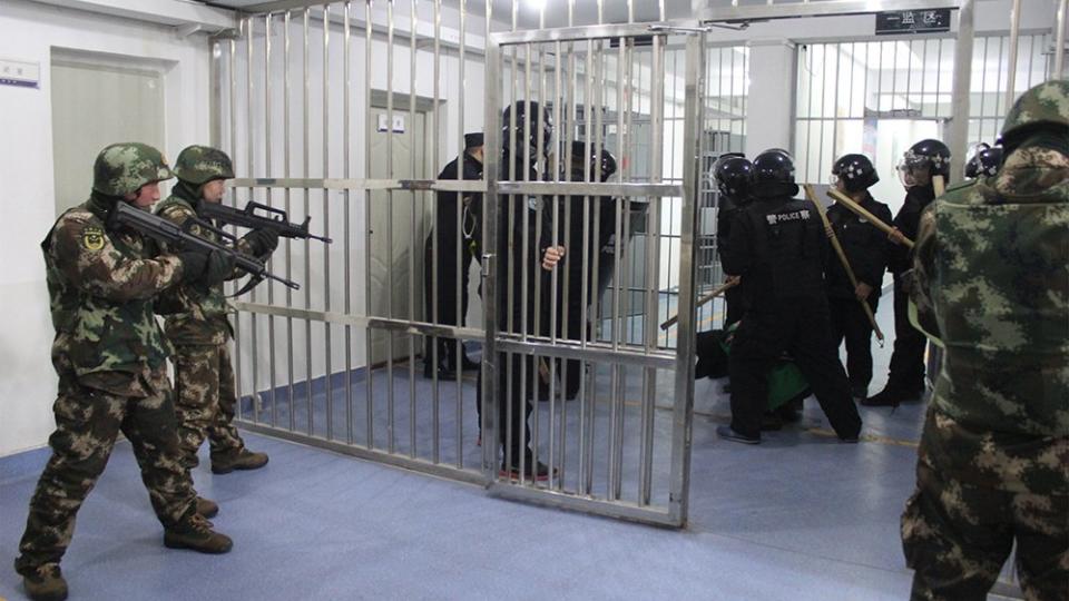 a detainee surrounded by armed police and military, pointing their guns