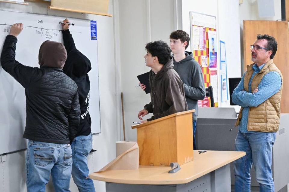 History professor Dominic Cerri, right, watches as a group of students write key events in their lives on the timeline on the whiteboard in his class at Sacramento City College on Wednesday, Dec. 6, 2023.