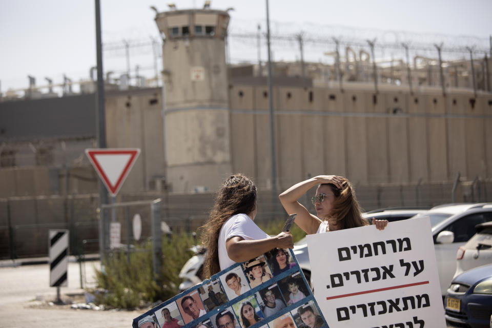 Members of the group Choosing Life, that includes relatives of Israelis killed in Palestinian attacks, protest outside of Ofer Prison near Jerusalem, Thursday, Sept. 9, 2021, after the escape of six Palestinian prisoners from Gilboa prison on Monday. At left is a poster depicting slain Israelis; at right is a poster that reads: "compassion for the cruel is cruel to the murdered." (AP Photo/Maya Alleruzzo)