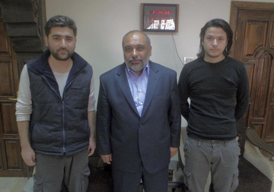 FILE - In this May 5, 2012, file photo provided by pro-Islamic aid group known by its Turkish acronym IHH, showing Turkish journalists Adem Ozkose, left, and Hamit Coskun, right, with the IHH Chairman Bulent Yildirim, centre, in Damascus, Syria. One of two journalists detained in Syria, Ozkose, is a devout Muslim who was on a Gaza-bound aid ship targeted in a deadly raid by Israel in 2010, and described the activists who died as "martyrs." Hamit Costun is a film school student who, ahead of his Syrian trip, ducked his father's disapproval by claiming he planned to visit Italy. Ozkose and Coskun are now the subject of complex negotiations for their release that reflect the opaque blend of regional rivalry and cooperation between Turkey, a foe of Syria's regime, and Iran, a staunch supporter said to be involved in the talks. (AP Photo/IHH, File)