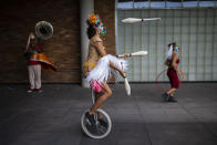 Performance artist Denise Lomeli juggles on a unicycle during a video recording of "The Giants Dreamers" outside the Museum of Modern Art (MAM) during the COVID-19 pandemic in Rio de Janeiro, Brazil, Tuesday, March 9, 2021. Brazil’s Congress approved in 2020 a financial lifeline for artists, as well as to maintain cultural venues and small troupes that had to cease activities. (AP Photo/Bruna Prado)