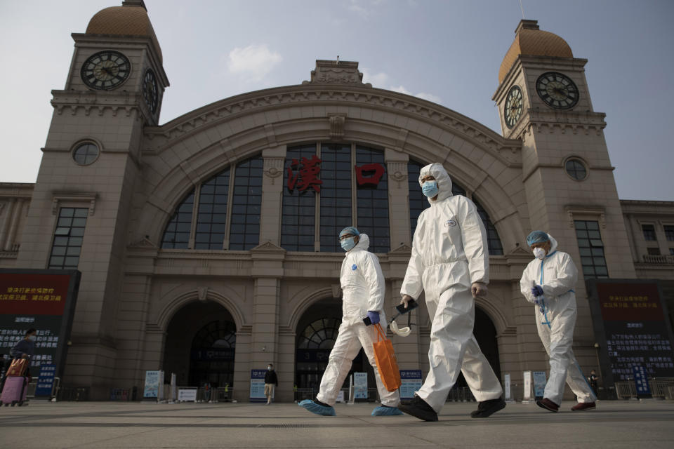 FILE - April 7, 2020, file photo, workers in protective overalls walk past the Hankou railway station on the eve of its resuming outbound traffic in Wuhan in central China's Hubei province. One year after Wuhan’s lockdown to curb the coronavirus, the Chinese city has long since sprung back to life. (AP Photo/Ng Han Guan, File)