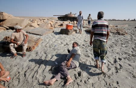 Fighters of Libyan forces allied with the U.N.-backed rest on a beach before they fire a shell with Soviet made T-55 tank at Islamic State fighters from a beach in Sirte, Libya, August 3, 2016. REUTERS/Goran Tomasevic