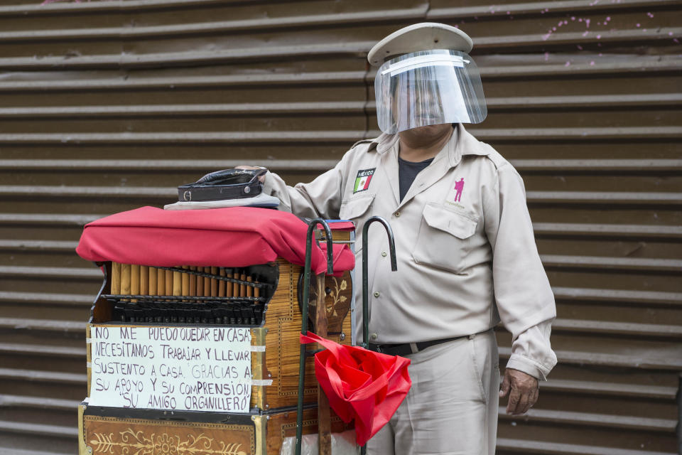 A barrel organ player wearing a face shield as a precaution against the spread of the new coronavirus, hopes for donations in Mexico City, Saturday, May 16, 2020. (AP Photo/Christian Palma)