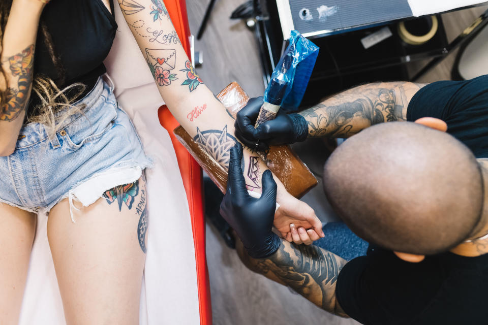 Tattooist drawing on arm of customer