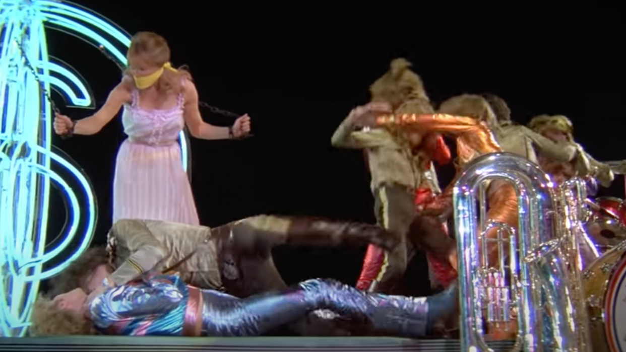 Aerosmith, the Bee Gees, and Peter Frampton brawl in 'Sgt. Pepper's Lonely Hearts Club Band,' while a captive Strawberry Fields, played by Sandy Farina, looks on. (Photo: YouTube).