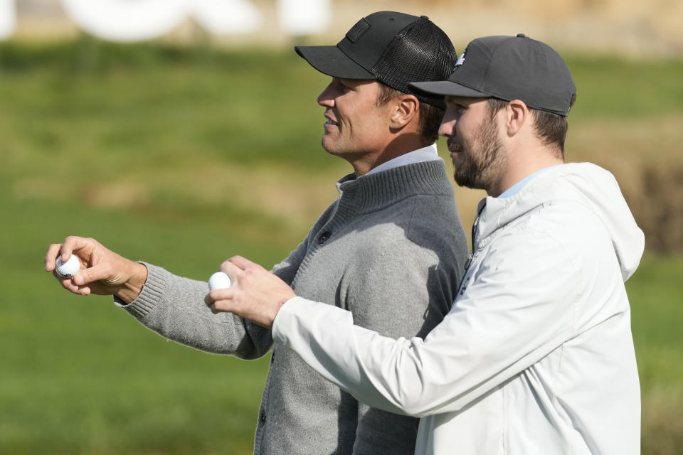 Former NFL quarterback Tom Brady, left, gestures next to Buffalo Bills quarterback Josh Allen on the 17th green at Pebble Beach Golf Links during the second round of the AT&T Pebble Beach National Pro-Am golf tournament in Pebble Beach, Calif., Friday, Feb. 2, 2024. (AP Photo/Eric Risberg)