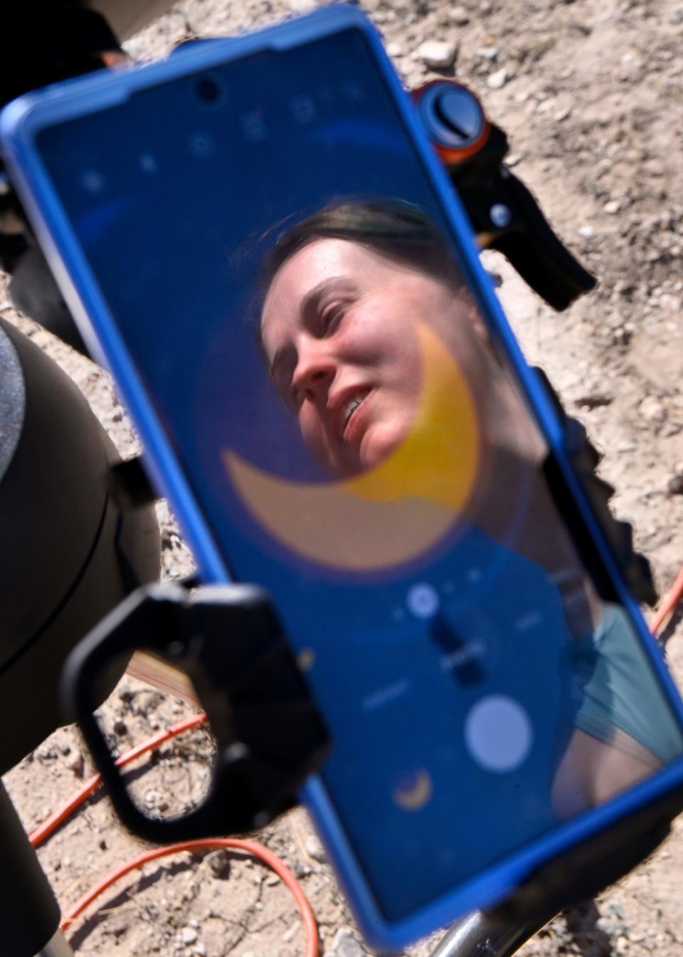 Sydney Griffin of San Angelo is reflected in the glass of her phone as it records the annual eclipse of the sun from a telescope at San Angelo State Park Oct. 14.