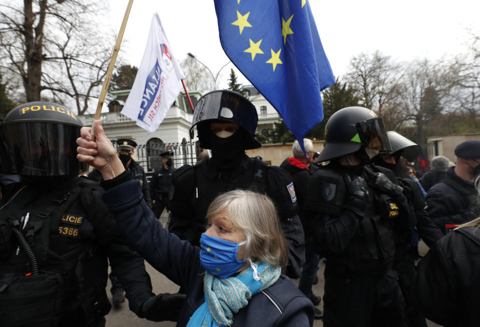 A woman waves a European Union flag in front of Russian Embassy in Prague, Czech Republic, Sunday, April 18, 2021. Czech Republic is expelling 18 diplomats identified as spies over a 2014 ammunition depot explosion. On Saturday, Prime Minister Andrej Babis said the Czech spy agencies provided clear evidence about the involvement of Russian military agents in the massive explosion that killed two people. (AP Photo/Petr David Josek)