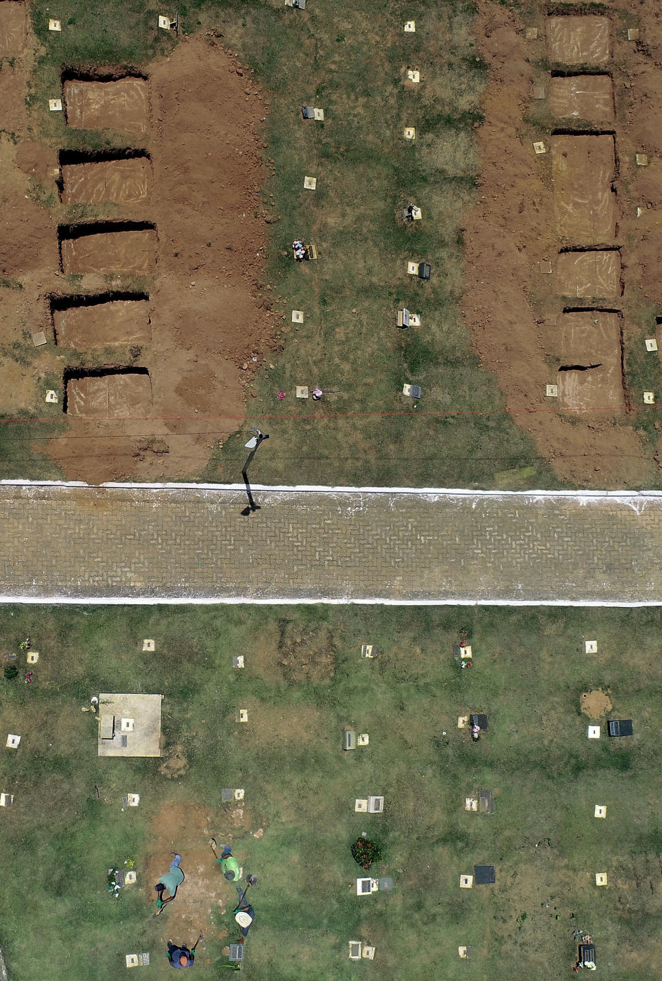 Cemetery workers prepare burial sites for the victims from the collapsed dam, in Brumadinho, Brazil, Tuesday, Jan. 29, 2019. Officials said the death toll was expected to grow "exponentially," since no one had been rescued alive since Saturday, a day after the collapse collapse on Friday led to an avalanche of mud. (AP Photo/Andre Penner