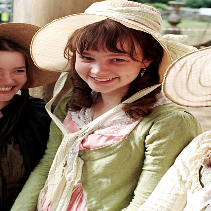 Close-up of Carey with other young women in period costumes and bonnets