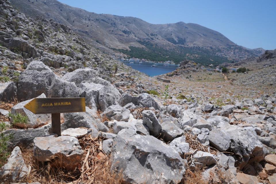 A direction sign on a rocky path in the hills of Pedi pointing toward Agia Marina, where the TV doctor’s body was discovered (Yui Mok/PA)