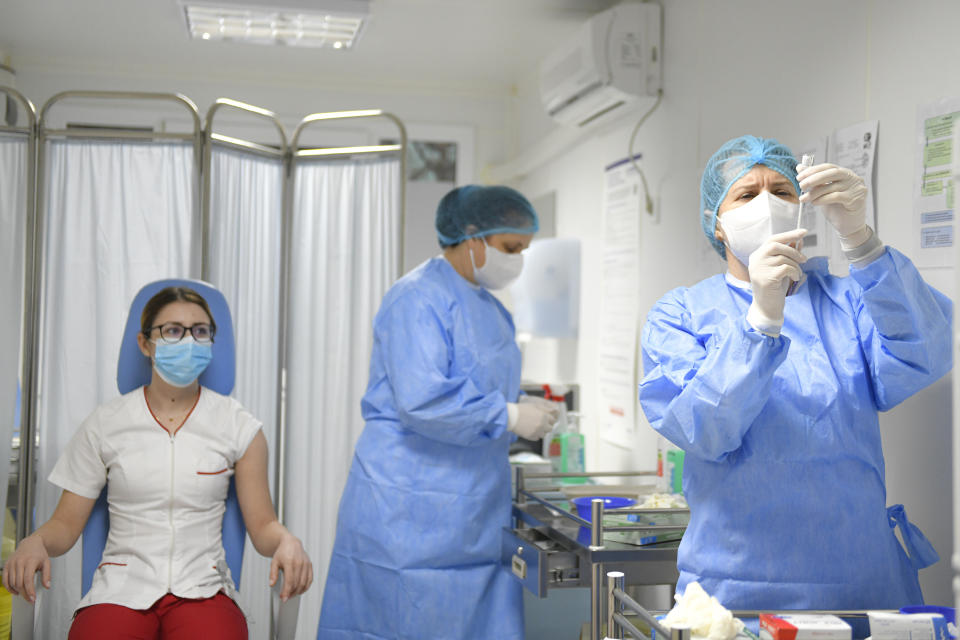 Mihaela Anghel, left, a Romanian nurse, waits to get the first COVID-19 vaccine administered in the country in Bucharest, Romania, Sunday, Dec. 27, 2020. Anghel is the nurse who registered and processed Romania's first official COVID-19 patient, on Feb. 27 2020. (AP Photo/Andreea Alexandru)