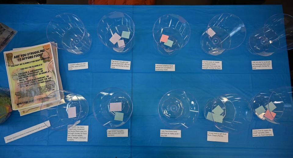 A table offers a visual representation of food insecurity as visitors answer questions with small pieces of paper during a Worcester State University fundraiser to collect money for the university's food pantry, Thea's Pantry.