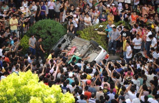 Protesters overturn a car near the local government office compound in Qidong, near the Chinese city of Shanghai, on July 28. Thousands of demonstrators protesting against alleged pollution from a paper factory in east China clashed with police Saturday, an AFP photographer said