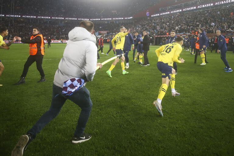 Un hincha de Trabzonspor persigue con el banderín del córner a un futbolista de Fenerbahce, tras los hechos violentos vividos este domingo en un duelo de la Superliga de Turquía