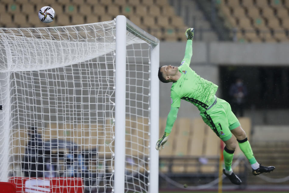 Real Sociedad's goalkeeper Alex Remiro jumps to save on a shot on goal by Athletic Bilbao's Inigo Martinez during the final of the 2020 Copa del Rey, or King's Cup, soccer match between Athletic Bilbao and Real Sociedad at Estadio de La Cartuja in Sevilla, Spain, Saturday April 3, 2021. The game is the rescheduled final of the 2019-2020 competition which was originally postponed due to the coronavirus pandemic. (AP Photo/Angel Fernandez)