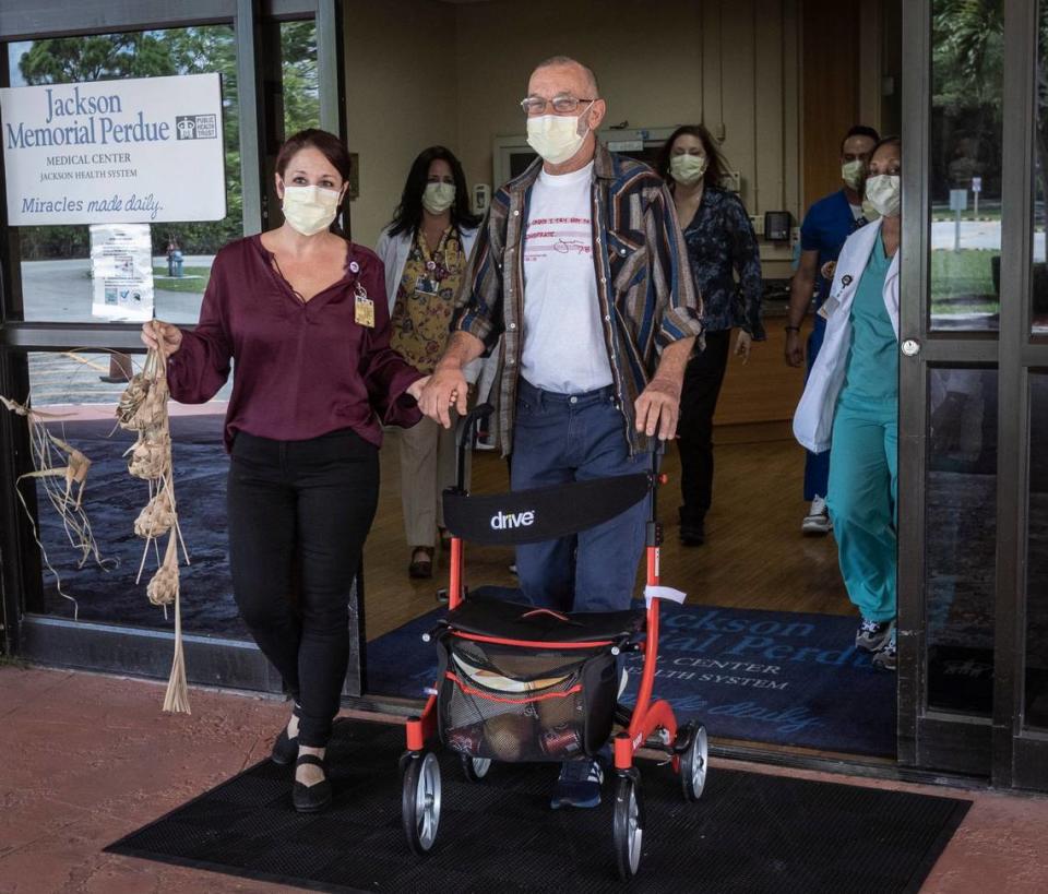 Dale Silvia, right, with social services director Sami Rudnick-Hoover, LCSW, leave Jackson Memorial Perdue Medical Center on Monday, June 21, 2021. They’re followed by physicians, nurses, therapists and support staff that had a hand in Dale Silva’s rehabilitation. Rudnick-Hoover is holding a piece given to her by Silva many years ago.