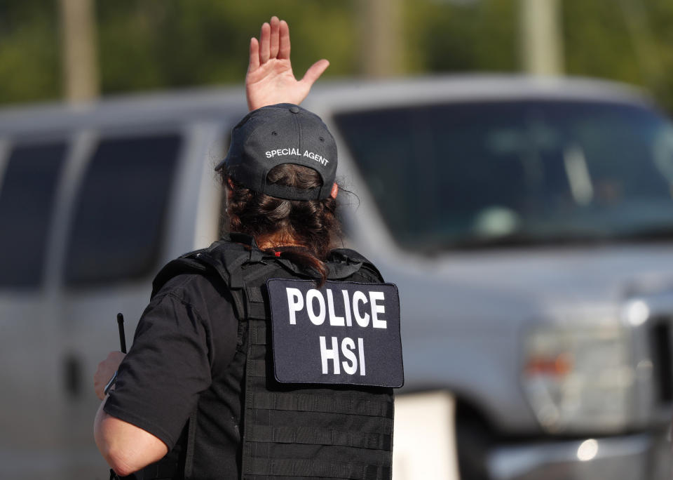 A federal agent directs a vehicle to approach following a raid by U.S. immigration officials at a Koch Foods Inc., plant in Morton, Miss., Wednesday, Aug. 7, 2019. U.S. immigration officials raided several Mississippi food processing plants on Wednesday and signaled that the early-morning strikes were part of a large-scale operation targeting owners as well as employees. (AP Photo/Rogelio V. Solis)