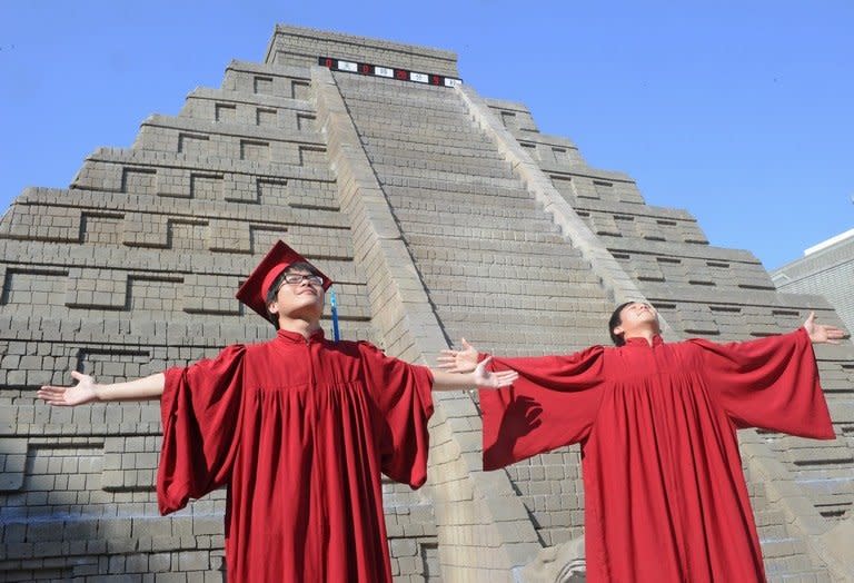 Students celebrate their graduation in front of a replica Mayan pyramid before a countdown by Taiwan's National Museum of Natural Science to help reassure the public it is not the end of the world, in Taichung on December 21, 2012. A global day of lighthearted doom-themed celebration culminated Friday in the jungle temples of the Mayan people of Central America, whose calendar sparks apocalypse fears