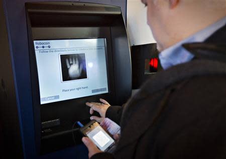 A customer registers his hand print before proceeding on the world's first ever permanent bitcoin ATM unveiled at a coffee shop in Vancouver, British Columbia October 29, 2013. REUTERS/Andy Clark