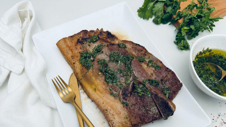 pork steak with chimichurri on white plate