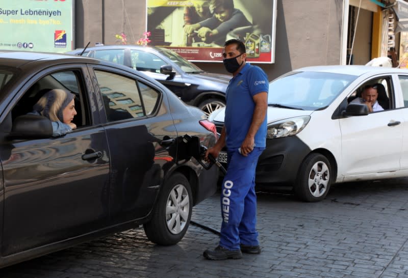 A worker wearing a protective face mask fills up a car with fuel, at a gas station in Beirut