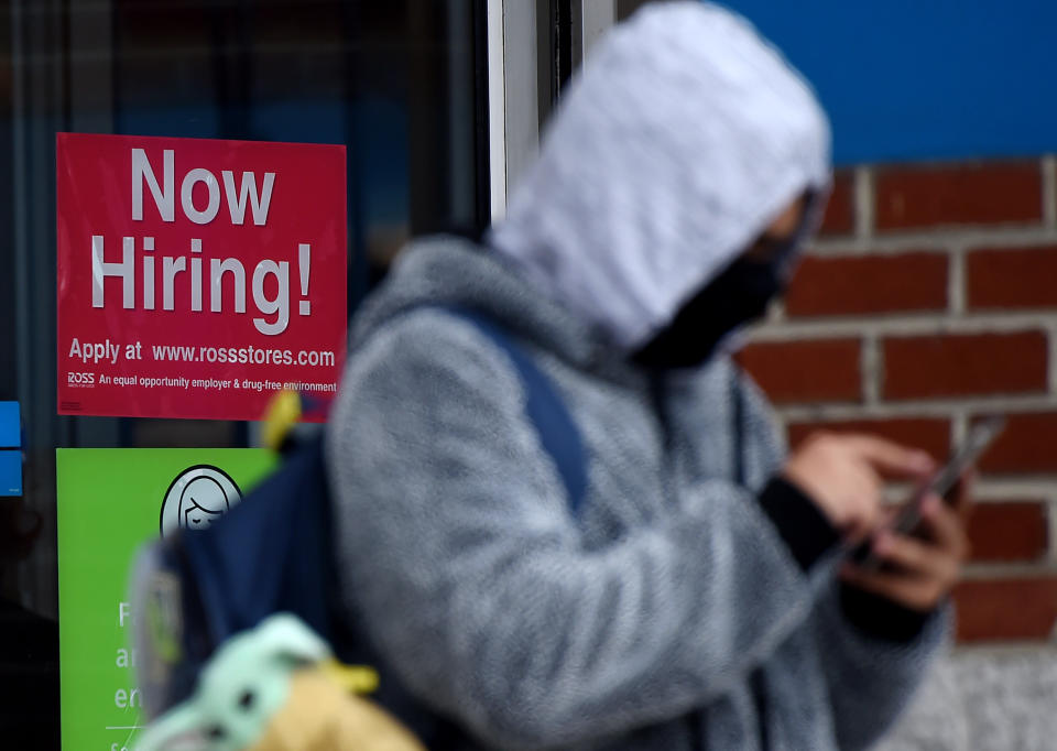 A man wearing a face mask stands next to a "Now Hiring " sign in front of a store in Arlington, Virginia, on Dec. 18. (Photo: OLIVIER DOULIERY/AFP via Getty Images)