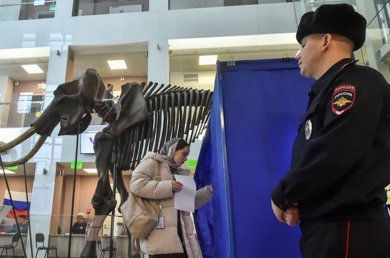 Una mujer entra en una cabina de votación cerca de un esqueleto gigante de mamut en un colegio electoral situado en la Universidad Estatal de Novosibirsk, en el último día de las elecciones presidenciales en Novosibirsk, Rusia